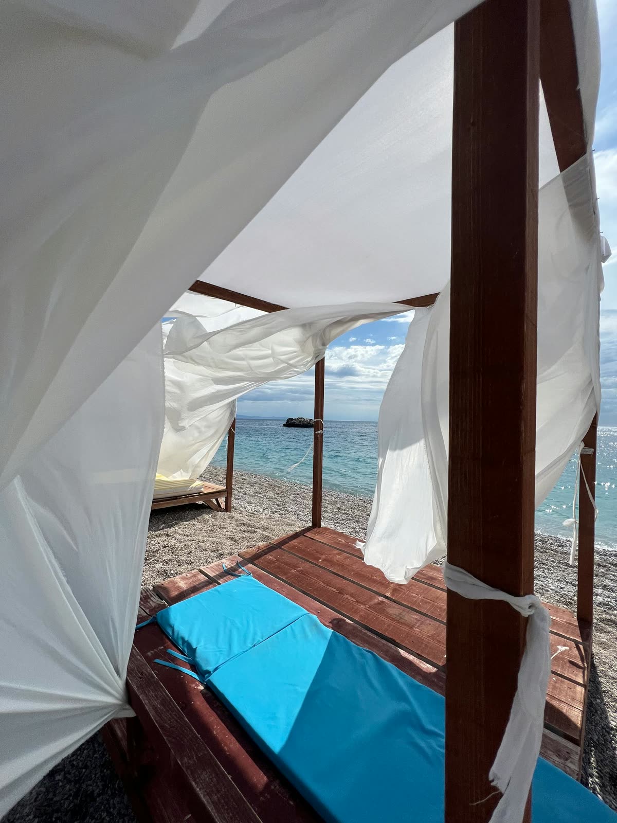 Day-beds with white cushions facing Corfu