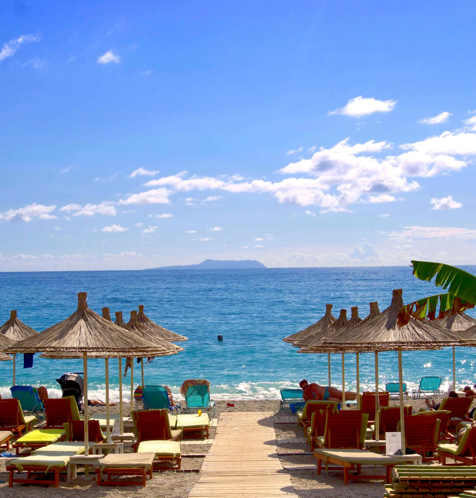 Straw parasols on the pebble beach in front of La Petite, Saranda
